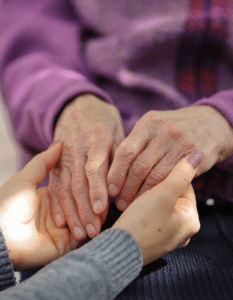 Caregiver and an elderly person holding hands