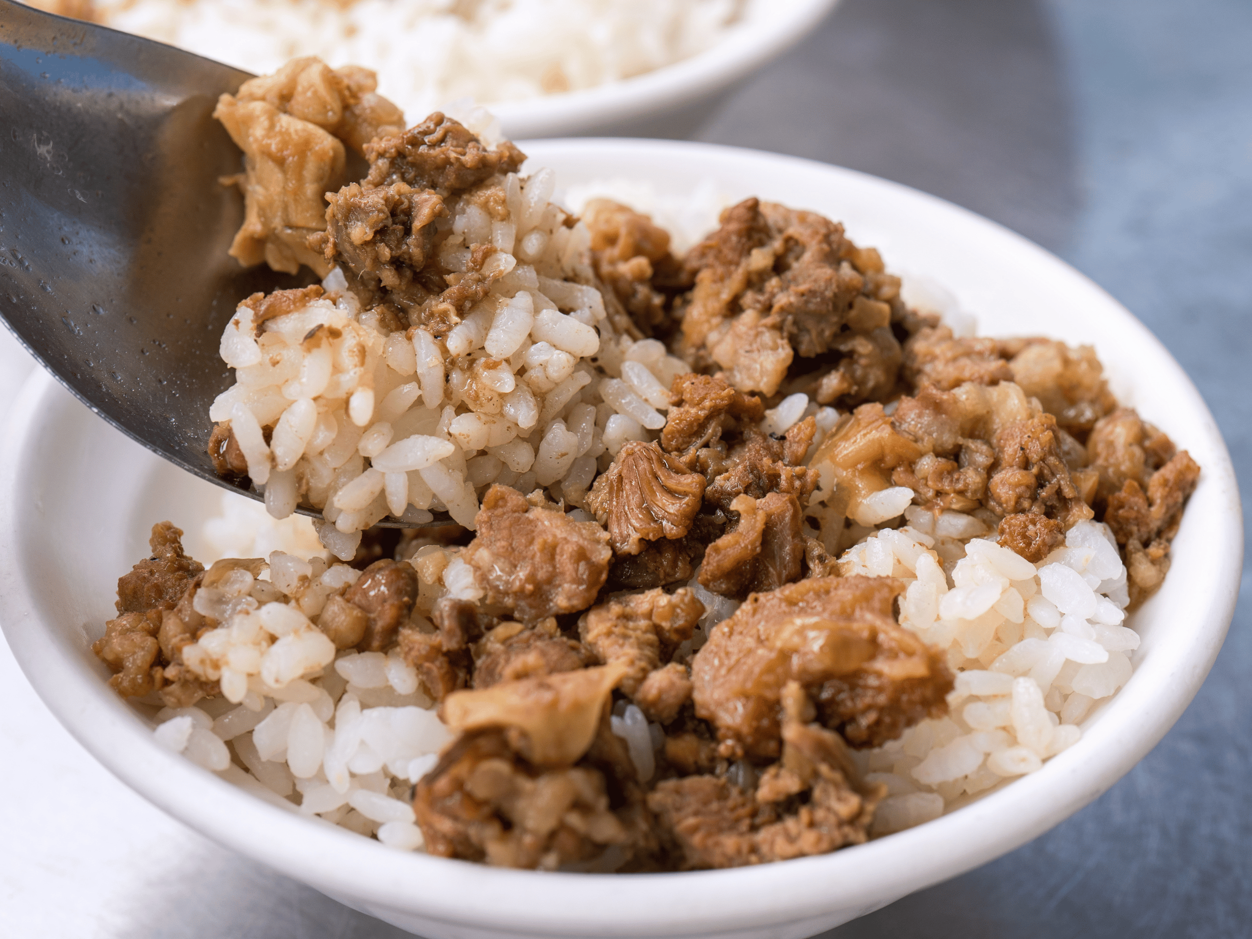 Beef over rice in a white bowl