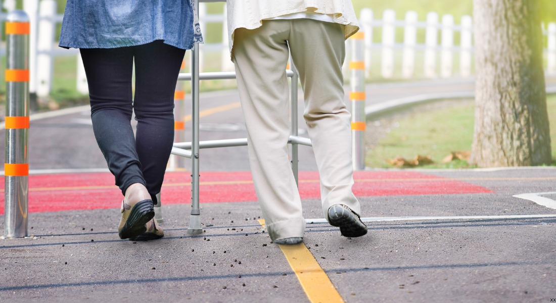 view from behind of 2 people walking, 1 with a cane